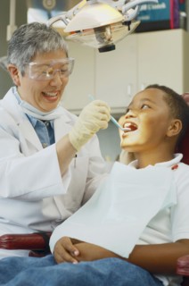 Senior Asian female dentist and African boy in dentist's chair