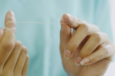 Close up of woman's hands with dental floss