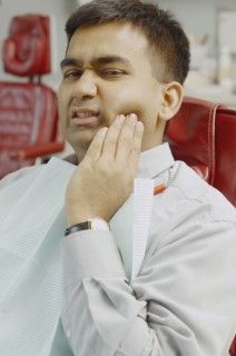 Indian man in dentist's chair with jaw pain