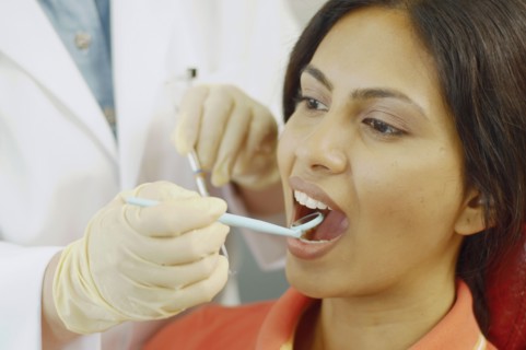 Dentist holding dental mirror in female patient's mouth