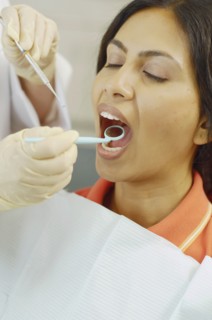 Dentist holding dental mirror in female patient's mouth
