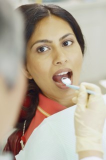 Dentist holding dental mirror in female patient's mouth