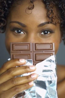 African woman holding chocolate bar in front of face
