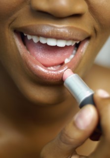 Close up of African woman applying lipstick