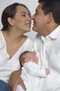 Hispanic parents hugging with baby