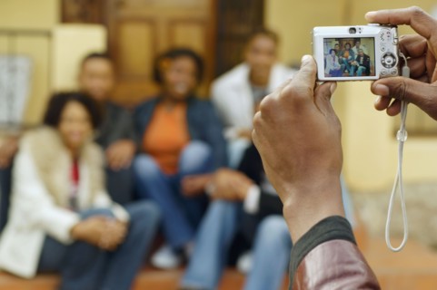 African man taking photograph of friends