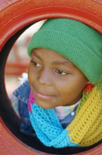 African girl leaning head through tire swing