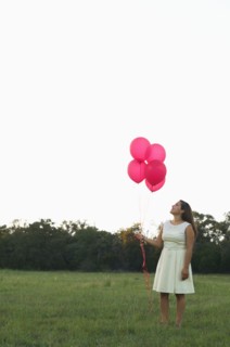 Mixed race woman with pink balloons in park