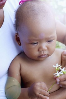 Mixed race baby holding flowers