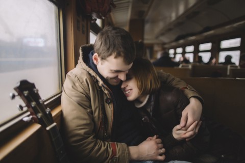 Smiling Caucasian couple with guitar hugging on train