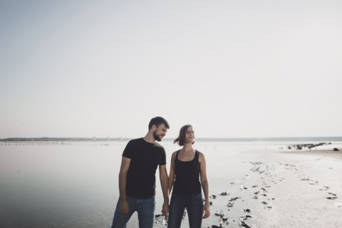 Caucasian couple holding hands on beach