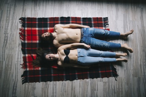 Caucasian couple laying flat on plaid blanket