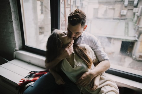 Caucasian couple kissing on window sill