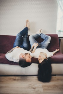 Caucasian couple laying upside-down on sofa