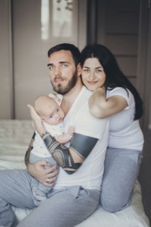 Portrait of Caucasian mother and father on bed with baby son