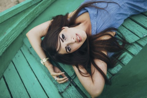 Caucasian woman laying on green boardwalk