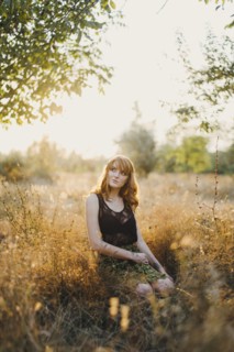 Pensive Caucasian woman kneeling in woods