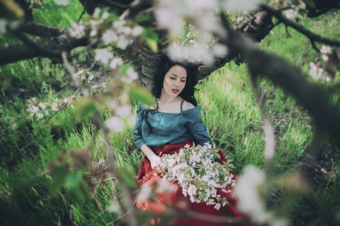 Caucasian woman leaning on tree holding flowers