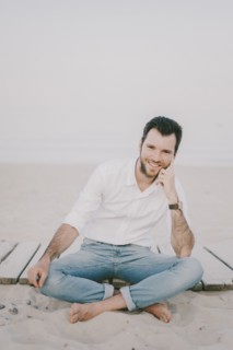 Caucasian man sitting on boardwalk at beach