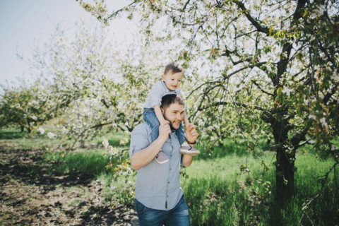 Caucasian father and son walking near tree