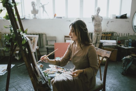 Serious Caucasian woman painting on canvas