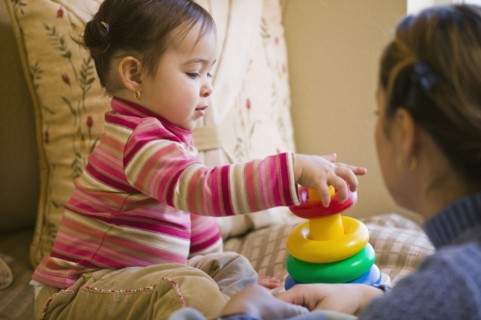 Hispanic mother watching daughter stack plastic rings