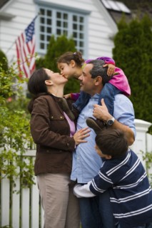 Mother kissing daughter while family watches
