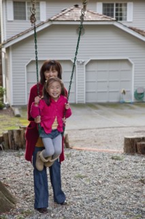Korean mother pushing daughter on swing
