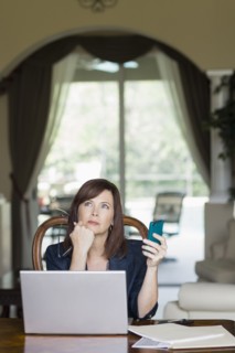 Caucasian businesswoman holding cell phone and looking up