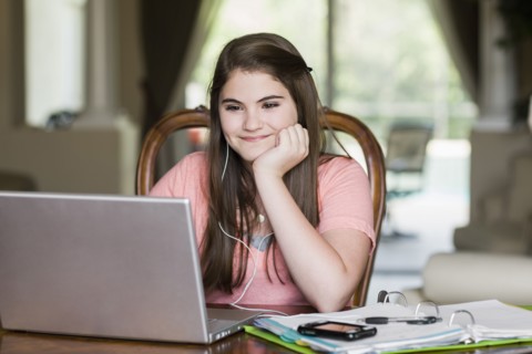 Caucasian girl using laptop and listening to mp3 player