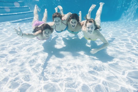 Smiling Caucasian teenagers underwater in swimming pool