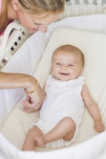 Caucasian mother looking at baby in bassinet