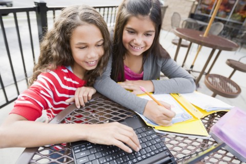 Smiling girls using laptop at cafe