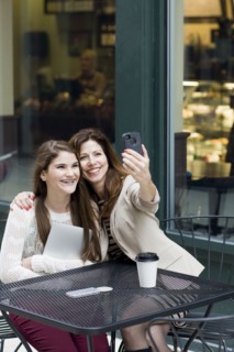 Caucasian mother and daughter taking picture in cafe