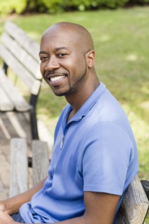 Black man smiling on park bench