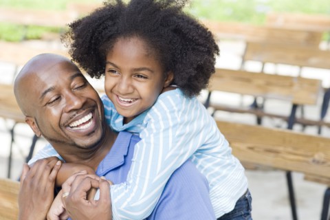 Father and daughter smiling on park bench