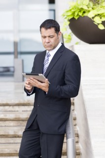 Hispanic businessman with tablet computer on city street