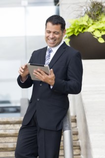 Hispanic businessman with tablet computer on city street