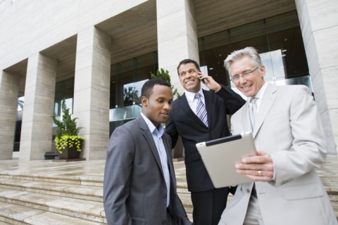 Businessmen using tablet computer on city street