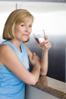 Caucasian woman drinking water in kitchen