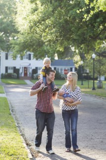 Caucasian family walking along neighborhood street