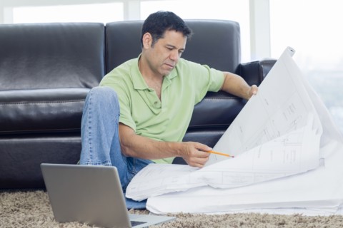Hispanic man examining blueprints in living room