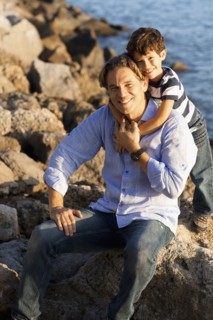 Caucasian father and son hugging on rocky beach