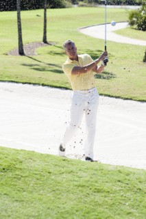 Caucasian man golfing from sand trap on golf course