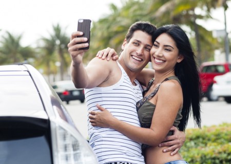 Hispanic couple taking cell phone selfie outdoors