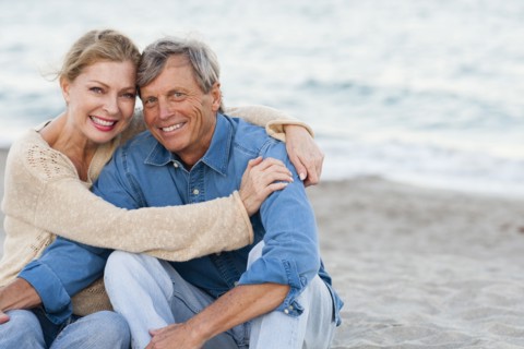 Older Caucasian couple hugging on beach