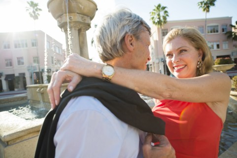 Older Caucasian couple hugging near fountain