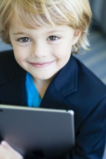 Smiling Caucasian boy in business suit holding digital tablet