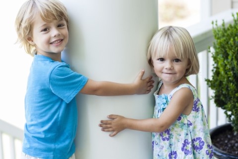 Caucasian children hugging column outdoors
