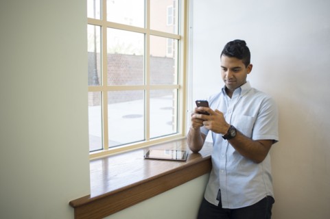 Asian businessman using cell phone and digital tablet at window